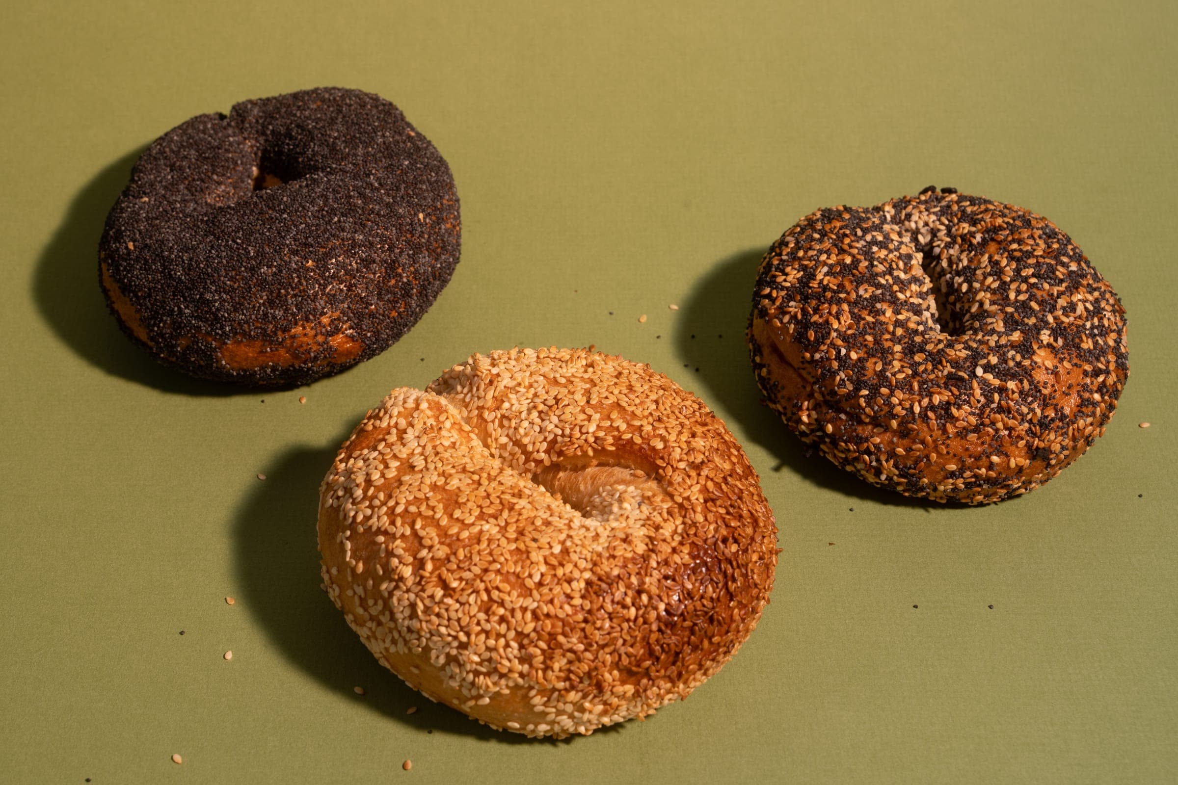 Poppy seed and everything bagels behind a golden sesame bagel
